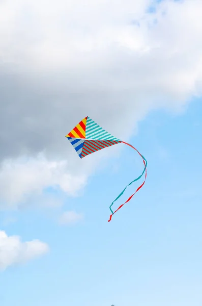 Cerf-volant multicolore sur un fond bleu ciel avec des nuages blancs. Symbole de paix et de sérénité. — Photo