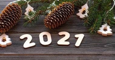 Çelenkli Noel ağacı dalları ve koyu ahşap arka planda 2021 numara. Mutlu yıllar 2021 'e.