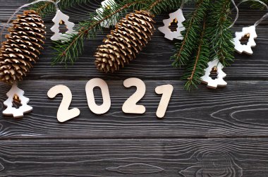 Çelenkli Noel ağacı dalları ve koyu ahşap arka planda 2021 numara. Mutlu yıllar 2021 'e.