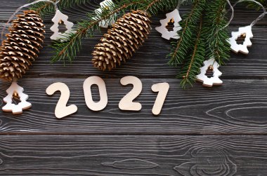 Çelenkli Noel ağacı dalları ve koyu ahşap arka planda 2021 numara. Mutlu yıllar 2021 'e.