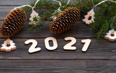 Çelenkli Noel ağacı dalları ve koyu ahşap arka planda 2021 numara. Mutlu yıllar 2021 'e.