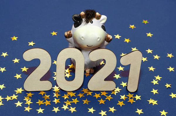 Christmas tree branches with a garland, Bull and the number 2021 on a blue background. Happy new year 2021.