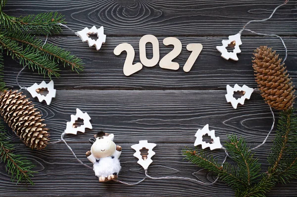 Julgransgrenar med en krans, Bull och nummer 2021 på en mörk träbakgrund. Gott nytt år till 2021. Stockfoto