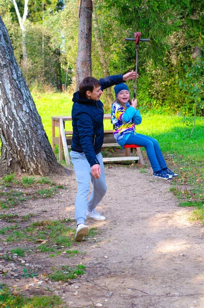 Adorable kid spending leisure time at playground. Outdoor shot of carefree preteen girl with father. — Stock Photo, Image