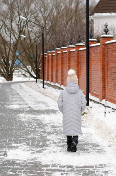 A girl in winter clothes and a hat playing with snow in a winter park. The child is outside during the winter holidays. — Stock Photo, Image