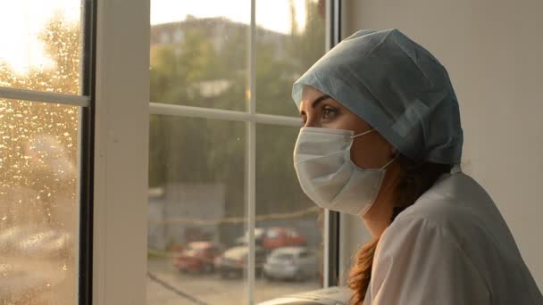 Mujer médico en máscara médica contra la ventana — Vídeo de stock