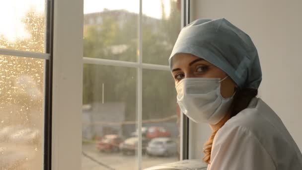 Ärztin in medizinischer Maske gegen das Fenster — Stockvideo