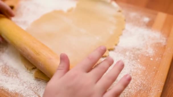 Manos de los niños primer plano desplegar la masa para pan de jengibre con un rodillo de madera. — Vídeos de Stock