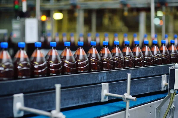 Plastikowe butelki piwa na przenośniku taśmowym w tle browaru — Zdjęcie stockowe
