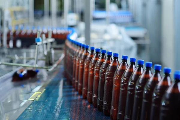 Botellas de cerveza de plástico en una cinta transportadora en el fondo de una cervecería — Foto de Stock