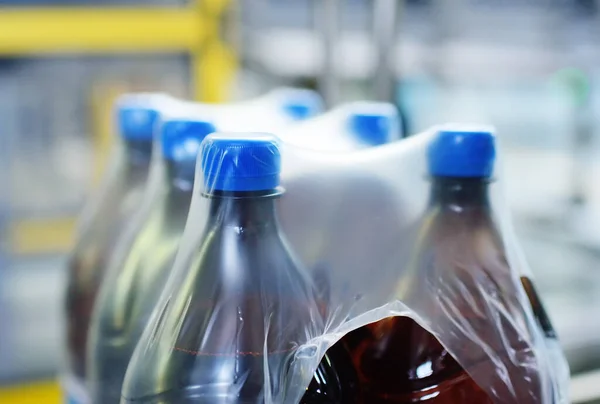 Embalaje de botellas de PET de plástico con cerveza o líquido en un envase de tetra de polietileno. —  Fotos de Stock