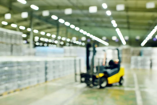 Cargador en el fondo de un enorme almacén industrial de alimentos con botellas de plástico PET con cerveza, agua, bebidas. —  Fotos de Stock