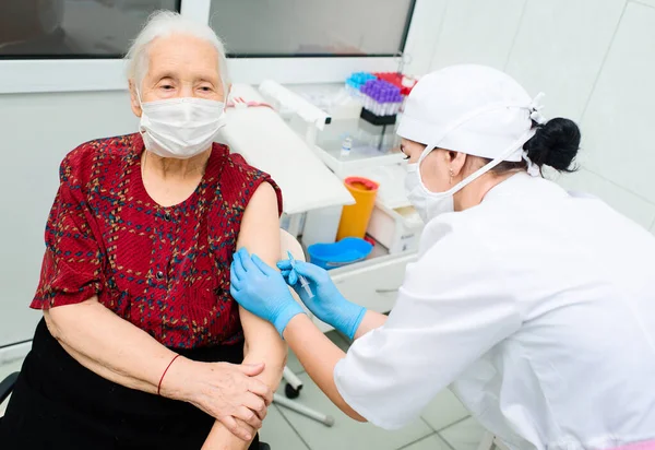 Médico ou enfermeiro injeta uma droga ou vacina em um ombro de mulheres idosas. — Fotografia de Stock