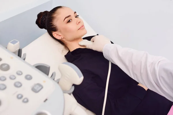 Doktor modern bir klinikte genç ve güzel bir kadının tiroit bezini ultrason ile muayene ediyor. Tiroid kanserinin önlenmesi. — Stok fotoğraf