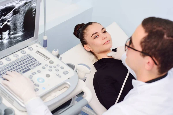 Az orvos ultrahangos vizsgálatot végez egy fiatal, csinos nő pajzsmirigyén egy modern klinikán. Pajzsmirigyrák megelőzése. — Stock Fotó