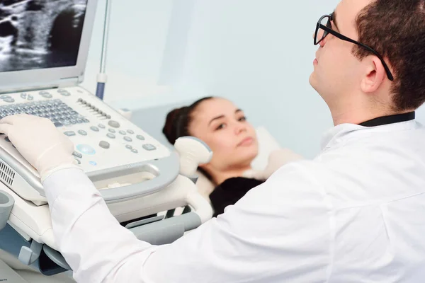 Lekarz przeprowadza badanie ultrasonograficzne tarczycy młodej, ładnej kobiety w nowoczesnej klinice. Zapobieganie rakowi tarczycy. — Zdjęcie stockowe