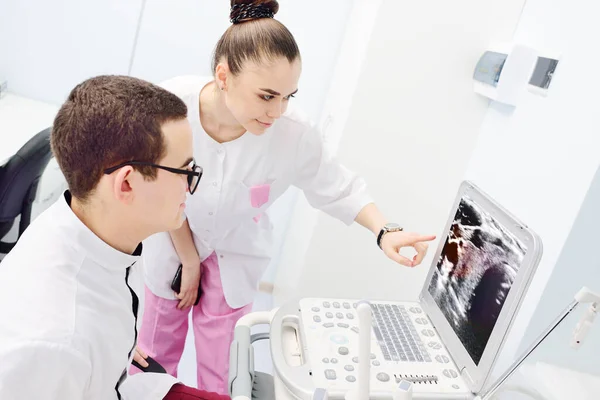 Fiatal orvosok - egy férfi és egy nő-felülvizsgálat, és megvitassák az eredmény egy ultrahang vizsgálata a pajzsmirigy — Stock Fotó