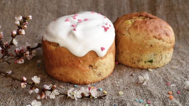 Decoración de la tarta de Pascua con azúcar glaseado y polvo de colores en el fondo de arpillera y ramitas con flores de primavera — Vídeos de Stock