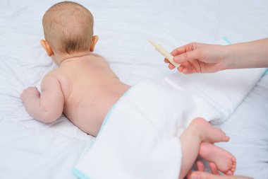 Yakın plan - bir bebeğin arka planına karşı annesinin elinde bir bebek gazı taşıyıcısı.