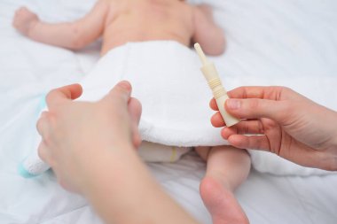 Yakın plan - bir bebeğin arka planına karşı annesinin elinde bir bebek gazı taşıyıcısı.