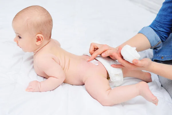 A mão das mães aplica um creme hidratante para bebês na pele dos meninos. Higiene do recém-nascido. — Fotografia de Stock