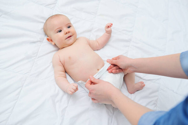 руки матери надевают на малышей пеленки.