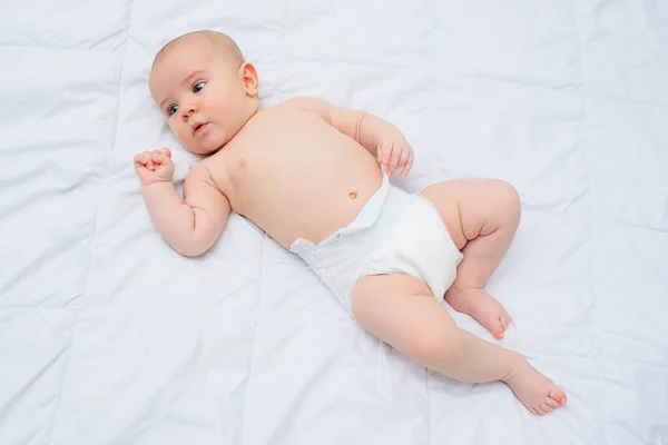 Bébé garçon dans une couche couchée sur un berceau sur un fond blanc. — Photo