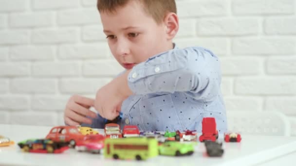 Junge spielt Spielzeugautos an einem weißen Tisch. — Stockvideo
