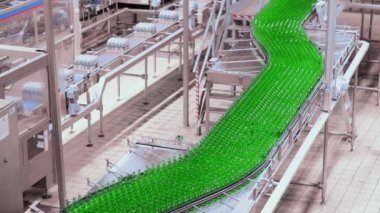 Bira fabrikasında bira doldurmak için sıra. Boş yeşil cam şişeler bira fabrikasında kuyrukta konveyör bandında hareket ediyor..