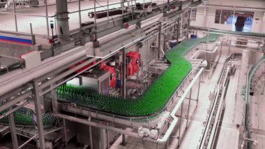 Bira fabrikasında bira doldurmak için sıra. Boş yeşil cam şişeler bira fabrikasında kuyrukta konveyör bandında hareket ediyor..
