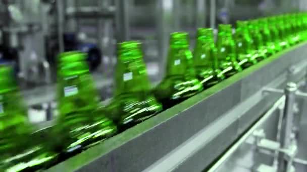 醸造所でビールを満たすためのライン。ビール工場のキューにコンベアベルト上を移動する空の緑のガラスボトル. — ストック動画