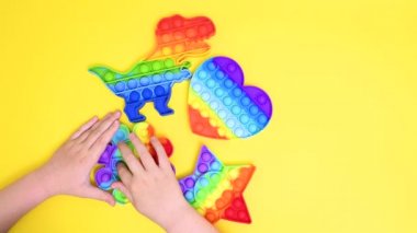 Çocuklar yakın plan çekimde lastik renkli pop it oyuncağıyla oynuyor.