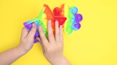 Çocuklar yakın plan çekimde lastik renkli pop it oyuncağıyla oynuyor.