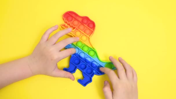 Childrens hands close-up playing with a rubber multi-colored pop it toy — Stock Video
