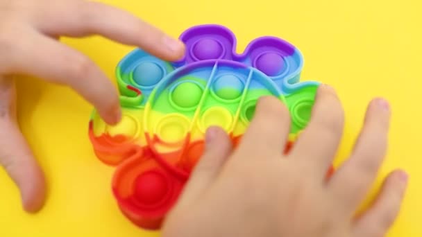 Παιδικά χέρια γκρο πλαν παίζει με ένα ελαστικό πολύχρωμο ποπ παιχνίδι — Αρχείο Βίντεο