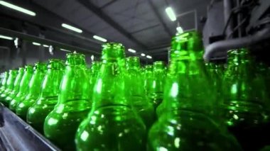 Bira fabrikasında bira doldurmak için sıra. Boş yeşil cam şişeler bira fabrikasında kuyrukta konveyör bandında hareket ediyor..