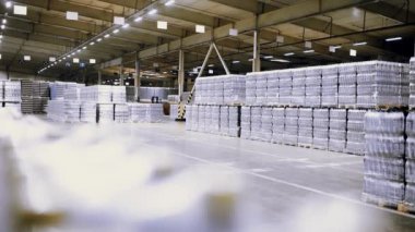 Arkaplanda bira, su ve içeceklerle dolu plastik PET şişeleri olan büyük bir endüstriyel gıda deposu var..