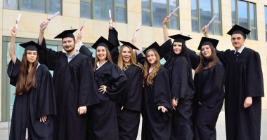 Siyahi öğrenci cübbesi ve kare şapkalı öğrenciler diploma almaktan ve eğitim sürecini tamamlamaktan memnuniyet duyuyorlar..