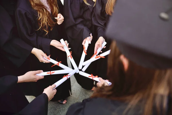 Estudiantes de posgrado con túnicas negras que posean diplomas o certificados de graduación de una institución de educación superior. —  Fotos de Stock