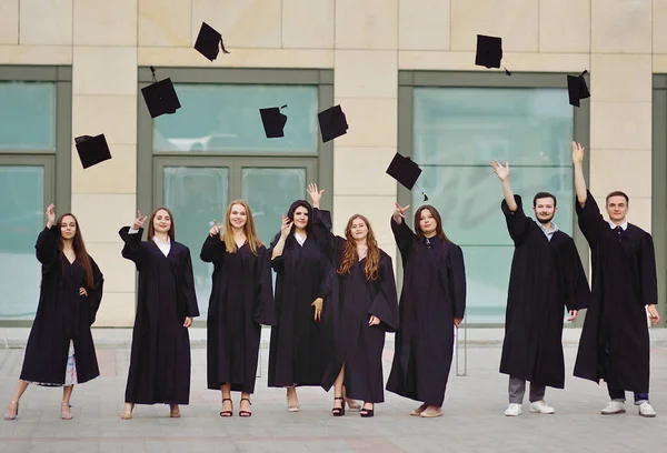 Studenten in gewaden geven academische caps en zijn blij om hoger onderwijs te ontvangen. — Stockfoto