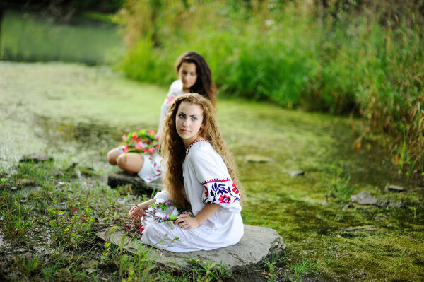 Two girls in the Ukrainian national clothes with wreaths of flow
