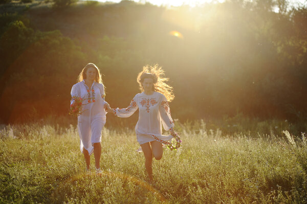two girls in the national Ukrainian clothes with wreaths of flow