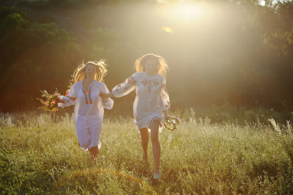 two girls in the national Ukrainian clothes with wreaths of flow