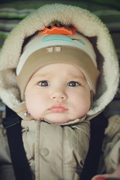 Bébé garçon avec des lèvres dodues dans le capot regardant à la caméra — Photo