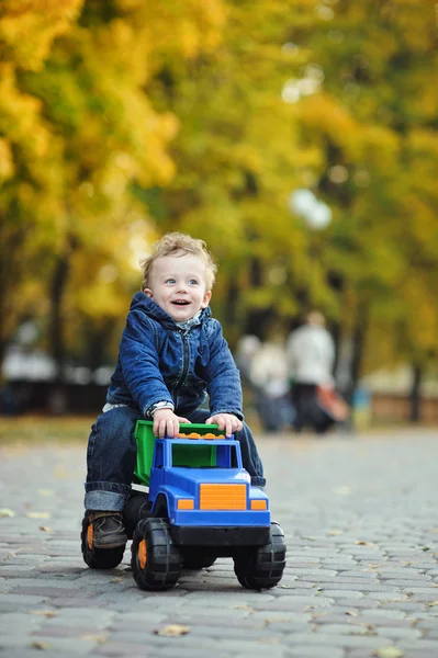 bir arka plan üzerinde bir oyuncak Araba sürme kıvırcık saçlı küçük çocuk bir