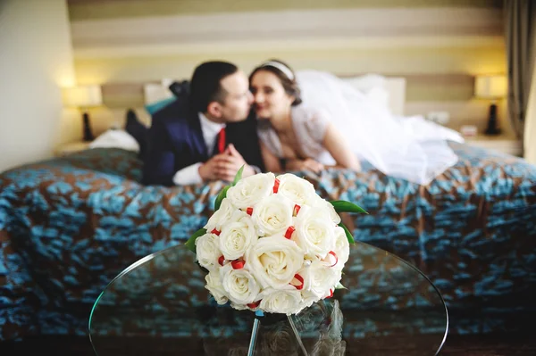 The bride and groom lying on the bed. In the foreground on the g