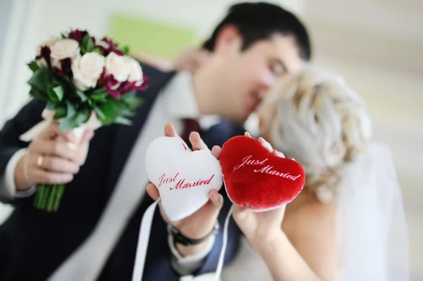 Les jeunes mariés tiennent les coussinets en forme de coeur avec le — Photo