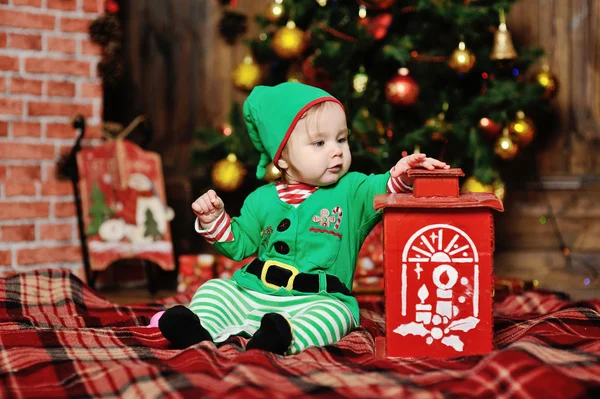 Niño vestido como un elfo sentado en un fondo a cuadros en el Chr —  Fotos de Stock