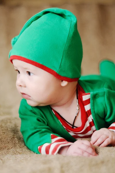 Child dressed as an elf lying on his stomach and looks away — Stock Photo, Image