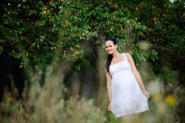 Gravid tjej i en vit sundress på bakgrund av aprikos t — Stockfoto